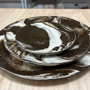 May include: Three ceramic plates with a brown and white marbled design. The plates are stacked on top of each other.