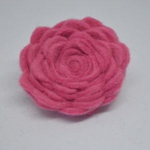 May include: A pink felt flower with a spiral design in the center.