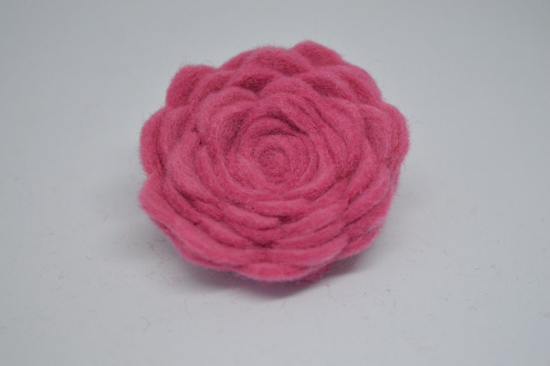 May include: A pink felt flower with a spiral design in the center.