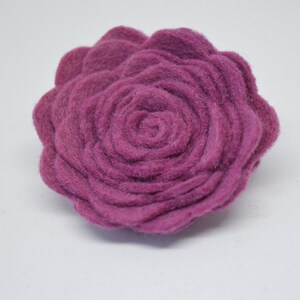 May include: A large, deep purple felt flower with a rosette design. The flower is made of multiple layers of felt, creating a three-dimensional effect.