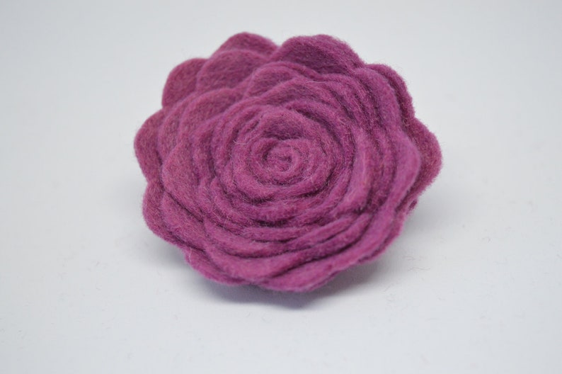 May include: A large, deep purple felt flower with a rosette design. The flower is made of multiple layers of felt, creating a three-dimensional effect.