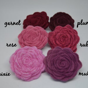 May include: Six felt flower embellishments in shades of pink and red, labeled with the names "garnet", "rose", "pixie", "plum", "ruby", and "mulberry".
