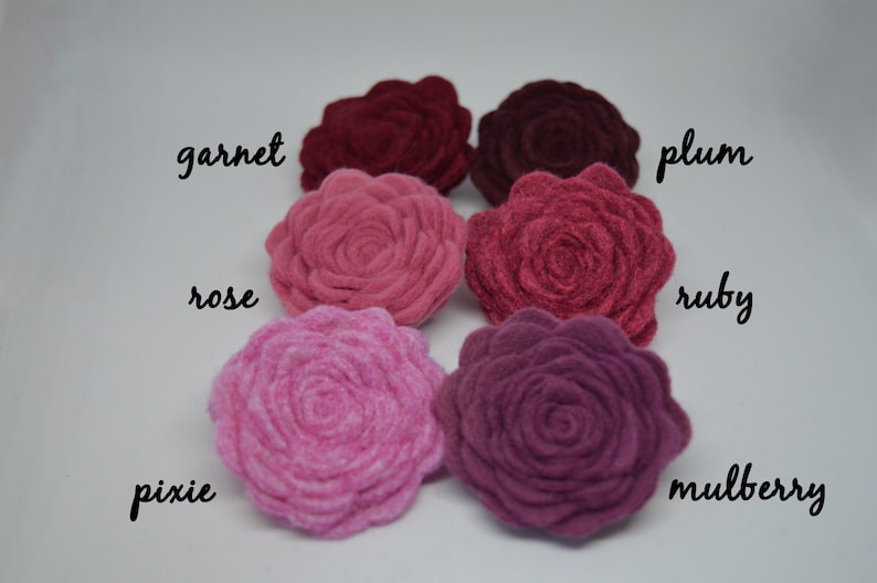 May include: Six felt flower embellishments in shades of pink and red, labeled with the names "garnet", "rose", "pixie", "plum", "ruby", and "mulberry".