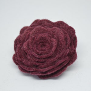 May include: A burgundy felt flower with a layered, rosette design.