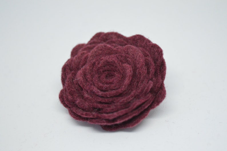 May include: A burgundy felt flower with a layered, rosette design.