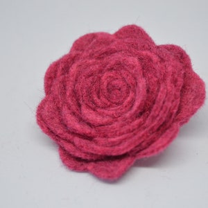 May include: A deep pink felt rose flower. The rose is made of multiple layers of felt, creating a textured and dimensional look.