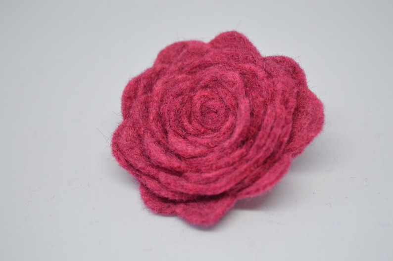 May include: A deep pink felt rose flower. The rose is made of multiple layers of felt, creating a textured and dimensional look.