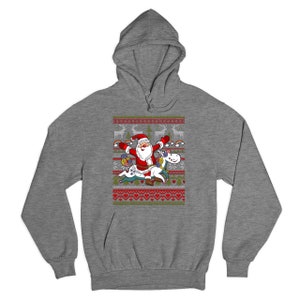 May include: A gray hooded sweatshirt with a Christmas-themed design featuring Santa Claus riding a unicorn. The design includes a red and green color scheme with a white background.