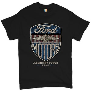 May include: Black t-shirt with a distressed Ford Motors logo. The logo, in a shield shape, includes the words "Ford Motors" and "Legendary Power 1903". The design uses red, white, and blue colours, reminiscent of the American flag.