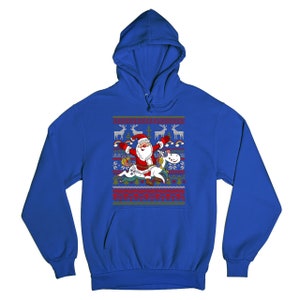May include: A royal blue hooded sweatshirt with a Christmas-themed design featuring Santa Claus riding a unicorn. The design includes reindeer, snowflakes, and a festive pattern.