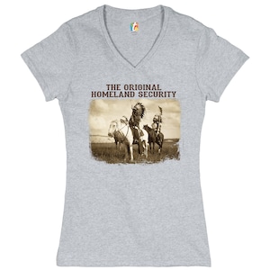 May include: Gray V-neck t-shirt with a vintage image of Native American warriors on horseback. The text "THE ORIGINAL HOMELAND SECURITY" is printed above the image.