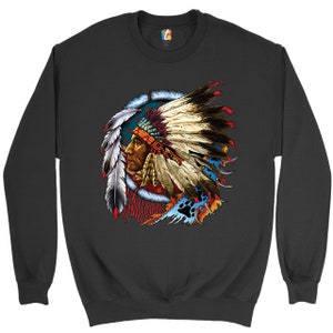 May include: A black sweatshirt with a colorful graphic print of a Native American chief wearing a headdress. The chief's face is visible and he is looking to the side. The headdress is made of feathers and beads. The background of the graphic is a blue and white circle with red and yellow accents.