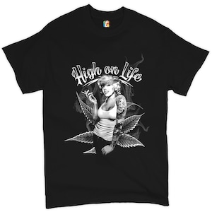 Op de afbeelding: Zwart T-shirt met een witte afbeelding van een vrouw met een bandana en tatoeages die een sigaret rookt. De vrouw is omringd door marihuanabladeren en de tekst "High on Life" staat boven haar.