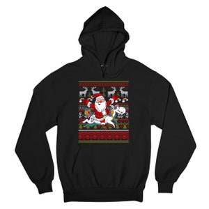 May include: Black hooded sweatshirt with a Christmas-themed design featuring Santa Claus riding a unicorn. The design includes a red and green color scheme with snowflakes, reindeer, and a Christmas tree.