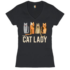 May include: Black v-neck t-shirt with a graphic of four cats in a row. The text "crazy cat lady" is printed below the cats.