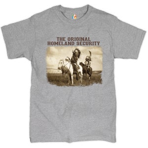 May include: A gray t-shirt with a vintage image of two Native American men on horseback. The text "THE ORIGINAL HOMELAND SECURITY" is printed above the image.