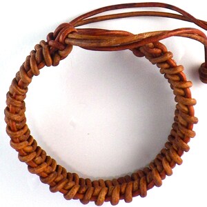 Puede incluir: Pulsera de cuero marr&oacute;n hecha a mano con un dise&ntilde;o tejido. La pulsera presenta un patr&oacute;n trenzado y lazos de cuero ajustables. El color marr&oacute;n c&aacute;lido y la textura sugieren una est&eacute;tica r&uacute;stica y natural. Circunferencia de unos 20 cm.