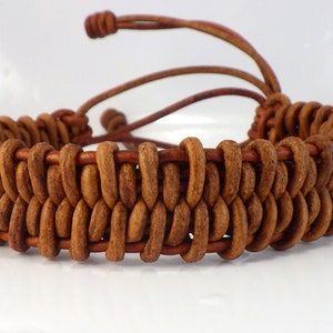 Puede incluir: Una pulsera de cuero marr&oacute;n con un dise&ntilde;o tejido. La pulsera presenta una construcci&oacute;n de doble capa con una serie de piezas de cuero redondeadas. Ajustable con un cord&oacute;n de cuero marr&oacute;n. Un accesorio artesanal.