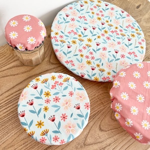 May include: Three reusable food covers with floral patterns. One cover is pink with white daisies, another is light blue with pink and yellow flowers, and the largest cover is light blue with pink and yellow flowers.