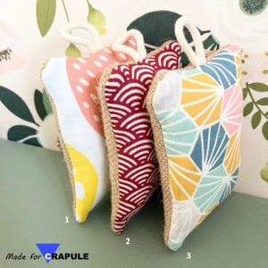 May include: Three decorative fabric squares with different geometric patterns. The squares are made of a natural fabric with a burlap trim. The patterns are a pink and white polka dot, a red and white wave pattern, and a blue, yellow, and pink geometric pattern.