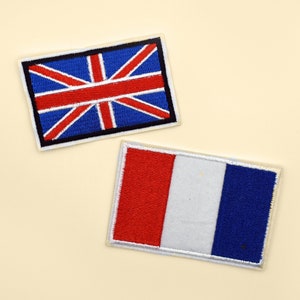 May include: Two embroidered fabric patches, one with the Union Jack flag of the United Kingdom and the other with the French flag. Both patches are white with colored embroidery.