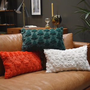 May include: A brown leather sofa with three throw cushions. The cushions are red, white and green. The sofa is in a living room setting.