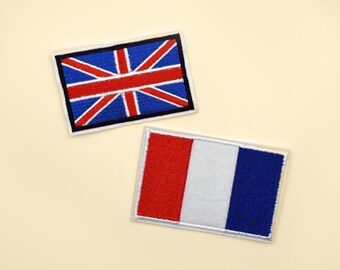 May include: Two embroidered fabric patches, one with the Union Jack flag of the United Kingdom and the other with the French flag. Both patches are white with colored embroidery.