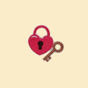 May include: Embroidered patch featuring a red heart-shaped padlock with a keyhole and a brown key. The patch is on a cream-colored background. The design is likely for clothing or accessories.