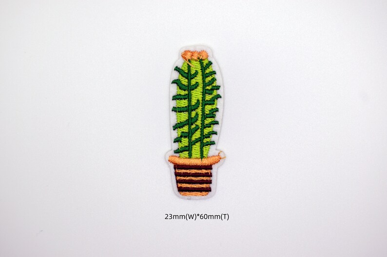 May include: Green embroidered cactus in a brown pot with orange accents. The cactus is 2.3 inches wide and 6 inches tall.
