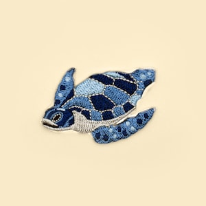 May include: A blue embroidered sea turtle patch with a detailed shell and flippers.