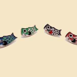 May include: Four enamel pins shaped like Japanese carp streamers, or koinobori. The pins are in red, black, green, and blue.