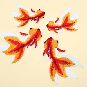 May include: Four embroidered iron-on patches of goldfish in orange, red, and white. The goldfish are facing different directions.