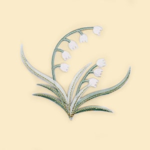 Puede incluir: Diseño bordado de lirios de los valles con flores blancas en forma de campana y hojas verdes. El diseño floral está sobre un fondo amarillo claro. Las hojas y los tallos tienen un aspecto detallado y texturizado.