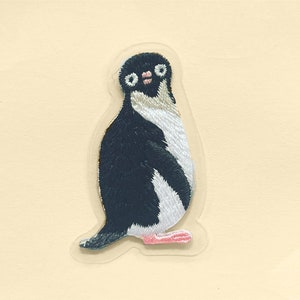 Op de afbeelding: Een geborduurde pinguïn patch in zwart en wit met roze voeten. De pinguïn staat rechtop met zijn vleugels ingeklapt.