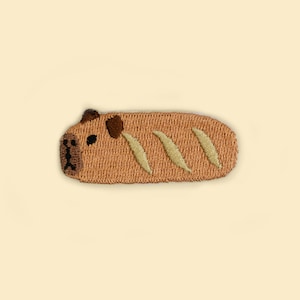 May include: A brown embroidered patch shaped like a loaf of bread with a cartoon pug face on one end.