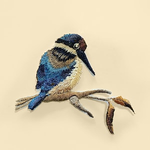 Op de afbeelding: Gestikt pleister van een blauwe en bruine ijsvogel die op een tak met bladeren zit.
