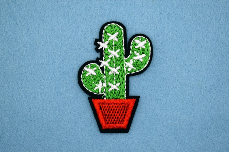 May include: Green embroidered cactus with white accents in a red pot. The cactus is a popular design for home decor and crafts.