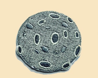 May include: A gray embroidered patch of the moon with craters.