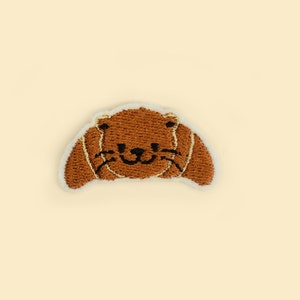 Strykbar Otter Croissant-lapp – Broderad djurapplikation för bageriälskare och udda presenter