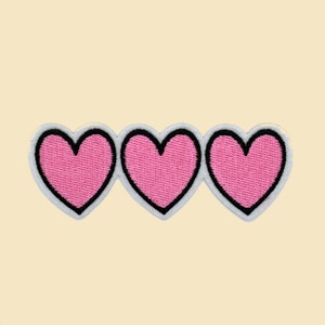 May include: Three pink heart-shaped patches with black outlines, arranged horizontally.