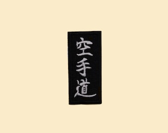 May include: Black rectangular patch with white embroidered Japanese characters that read "Karate-do".