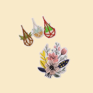 May include: Embroidered patches featuring botanical designs. Three patches depict hanging planters with plants, in brown, white, and red. A fourth patch shows a floral bouquet with pink, yellow, and blue accents. All patches have white borders.