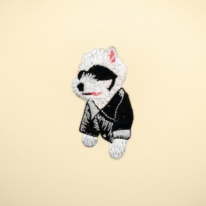 May include: White embroidered patch of a dog wearing sunglasses and a black leather jacket.