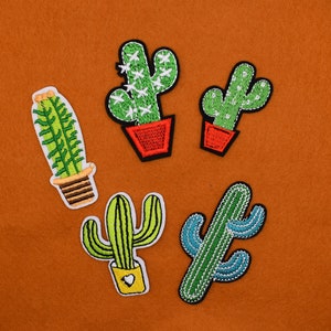 May include: Five embroidered cactus patches in different styles and colors. The patches are on a brown felt background.