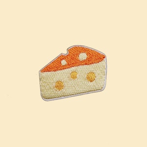 May include: An embroidered patch of a wedge of cheese with holes, in yellow and orange.