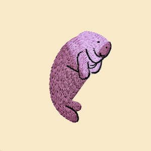 May include: An embroidered illustration of a manatee, a large, gentle sea mammal, in pink.
