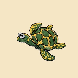Pode incluir: Um remendo bordado de uma tartaruga marinha verde e amarela. A tartaruga tem uma aparência de desenho animado com olhos grandes e um sorriso largo.