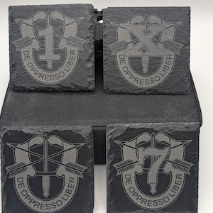 May include: Four black slate coasters with a gray engraved design of the 1st, 10th, and 75th Airborne Division insignia. Each coaster features the words "De Oppresso Liber" in a circle around the insignia.