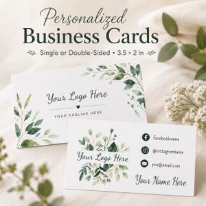 May include: Two white rectangular business cards measuring 3.5 by 2 inches, featuring watercolor green leaf illustrations. The cards display text placeholders for a logo, tagline, name, and social media handles with Facebook, Instagram, and email icons.