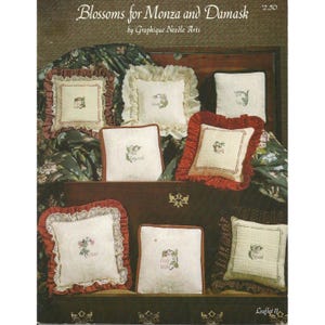 May include: A collection of decorative throw pillows with floral embroidery. The pillows feature various designs, including square and rectangular shapes, with ruffled or lace edges. The color palette includes cream, red, and green, with the text "Blossoms for Monza and Damask".